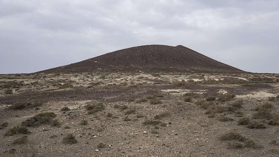 Montaña Roja's volcanic cone above sandy, rocky ground and low vegetation