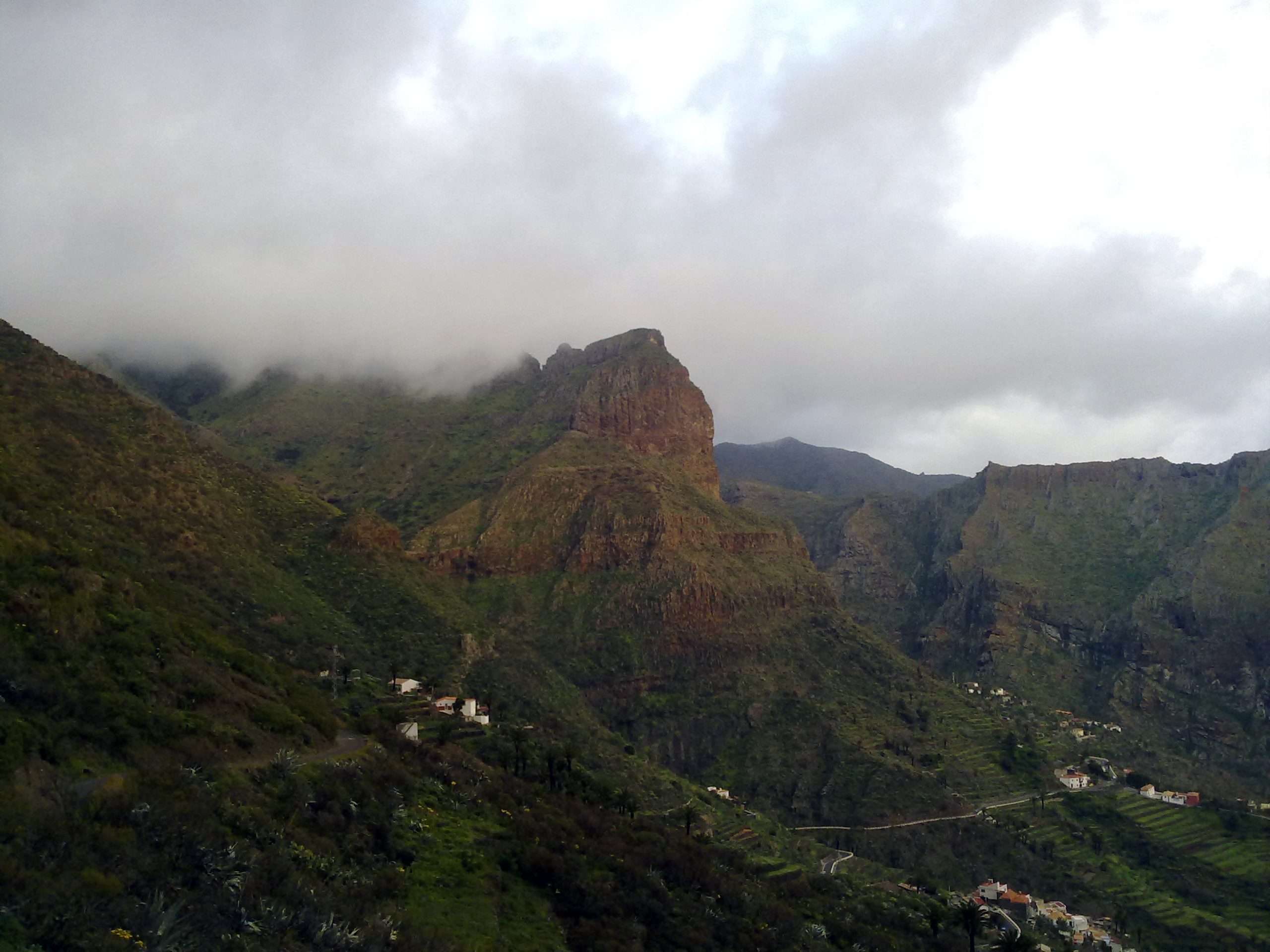 Panorámica del valle de Masca con casas dispersas y nubes sobre las montañas