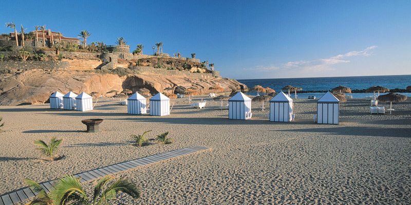 Arena, pasarela y casetas junto al mar en Playa del Duque